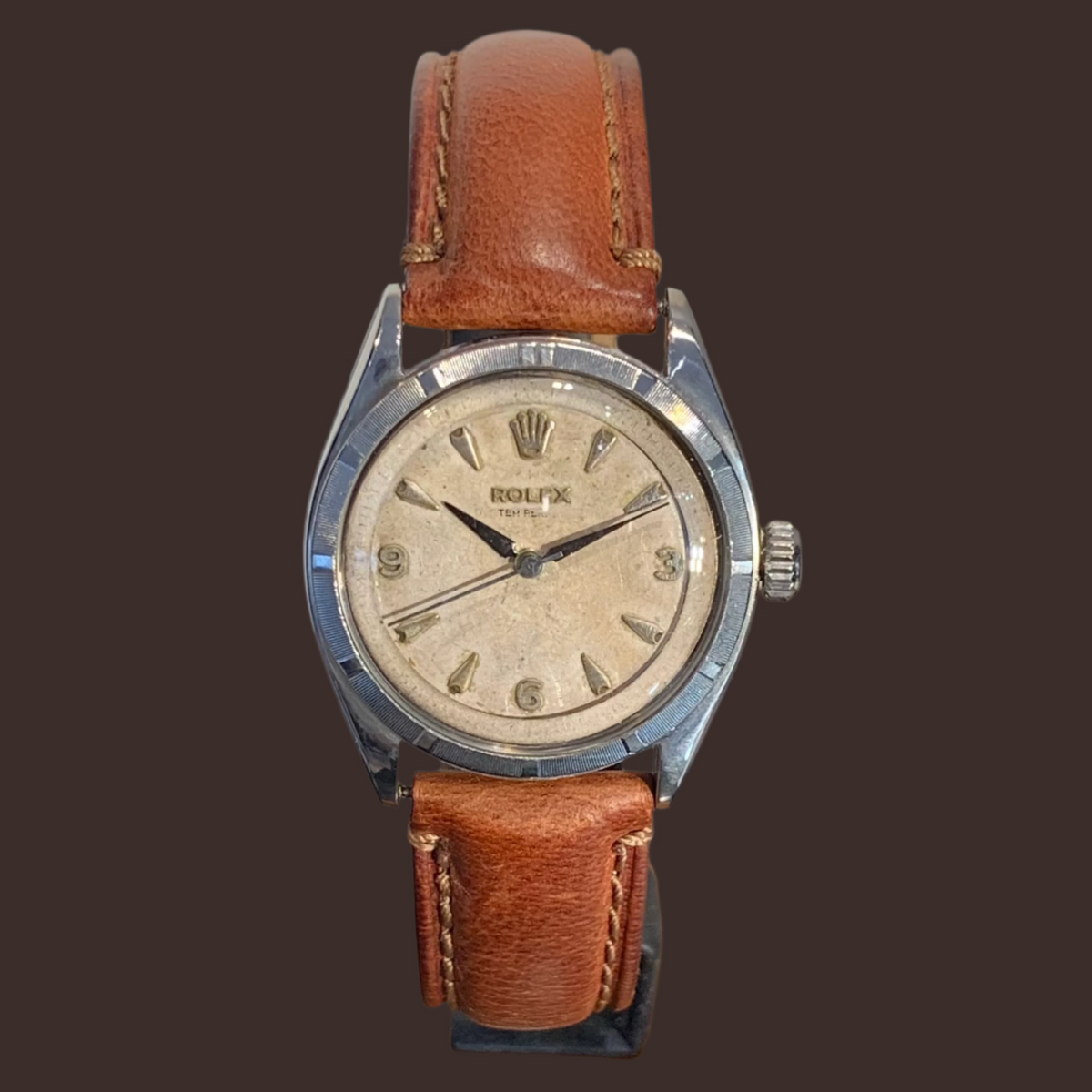 Vintage Rolex Oyster Perpetual with a brown leather strap and a silver dial.